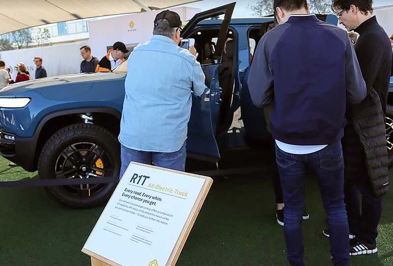Interested attendees at Fully Charged LIVE USA peer into a Rivian R1T on display