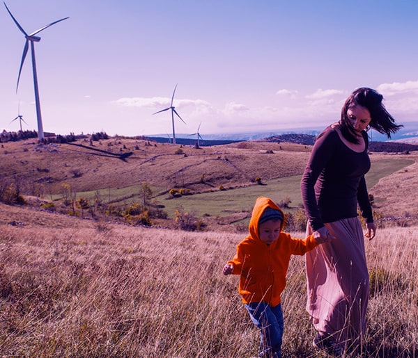 Mother and child walking in the clean air by wind turbines